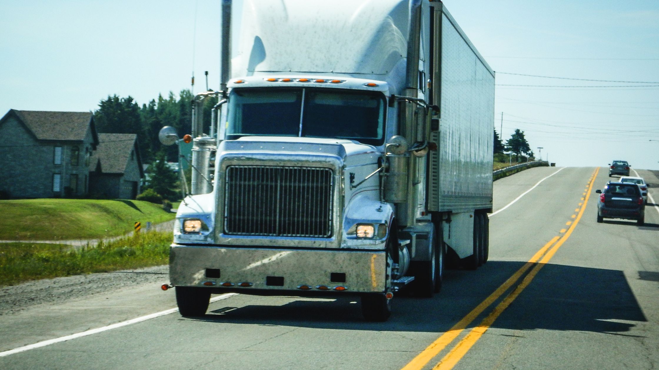 An image of a large semi-truck driving on one of the most dangerous trucking routes in Dallas, Texas, with other vehicles in close proximity on a sunny day, highlighting the importance of road safety in areas with heavy truck traffic.