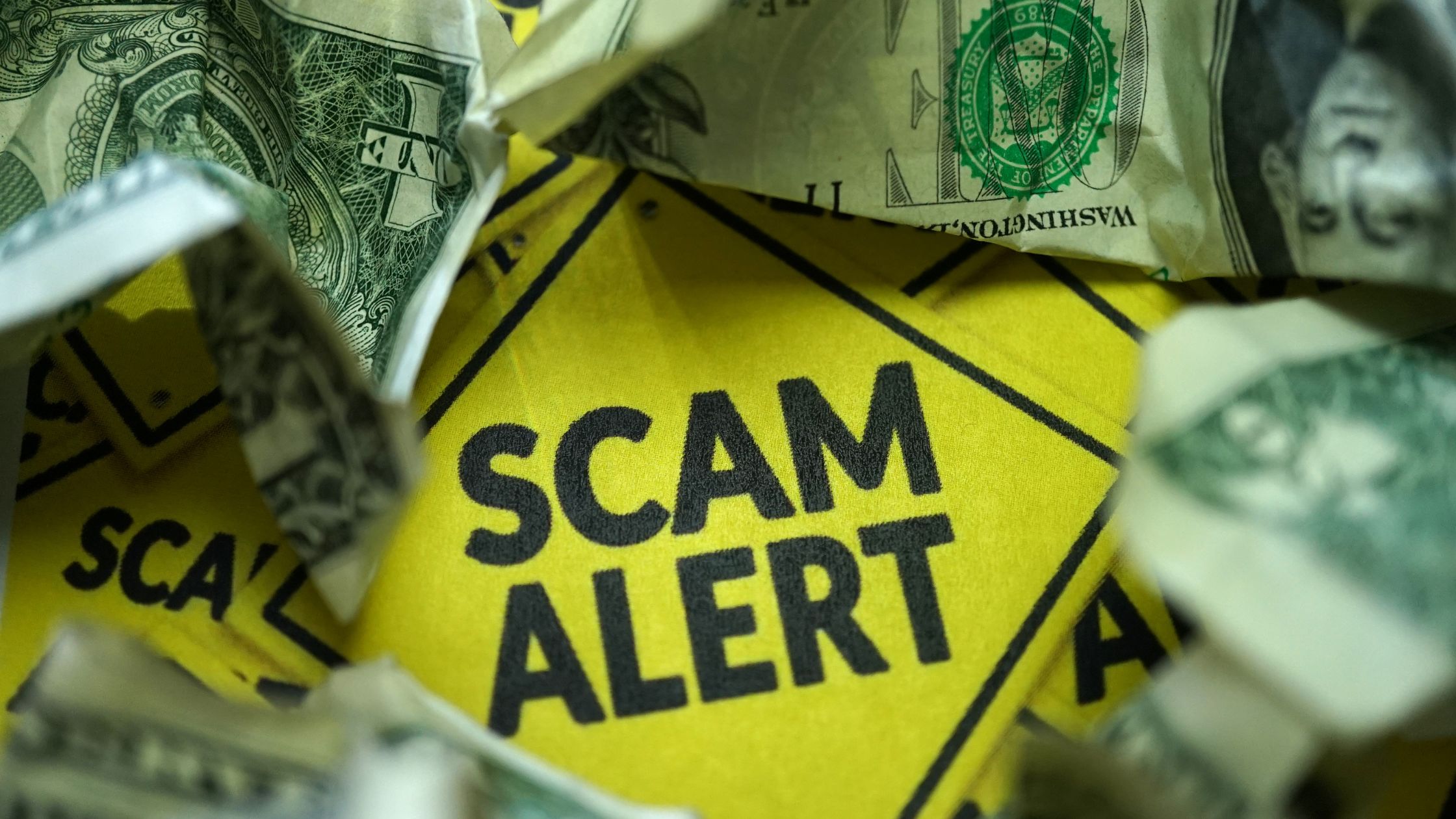 Crumpled dollar bills against a yellow "SCAM ALERT" sign, illustrating the need for vigilance against scams and misinformation regarding Social Security Disability.